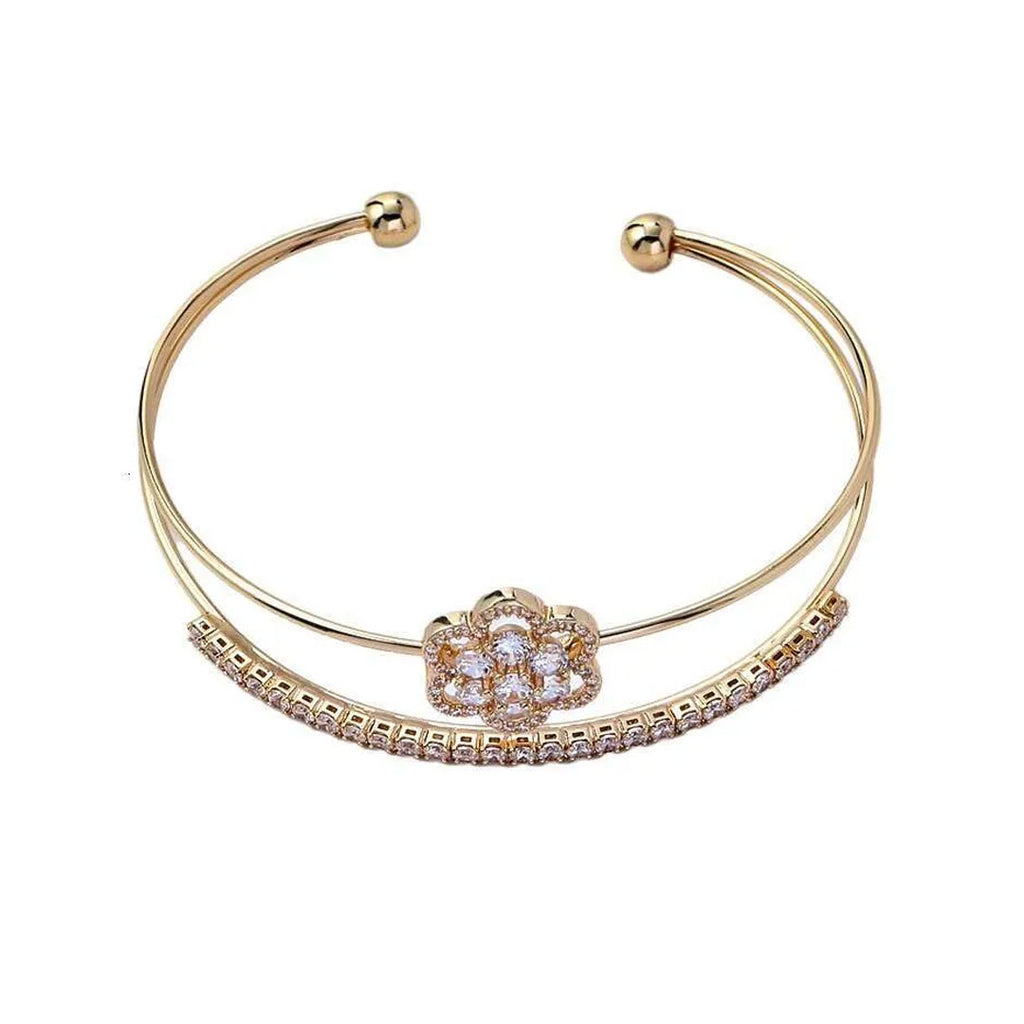 Gold bracelet with a floral clasp on a white background