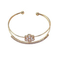 Gold bracelet with a floral clasp on a white background