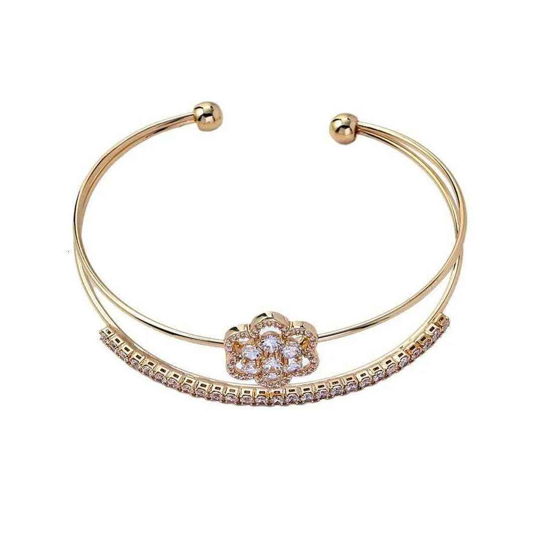 Gold bracelet with a floral clasp on a white background