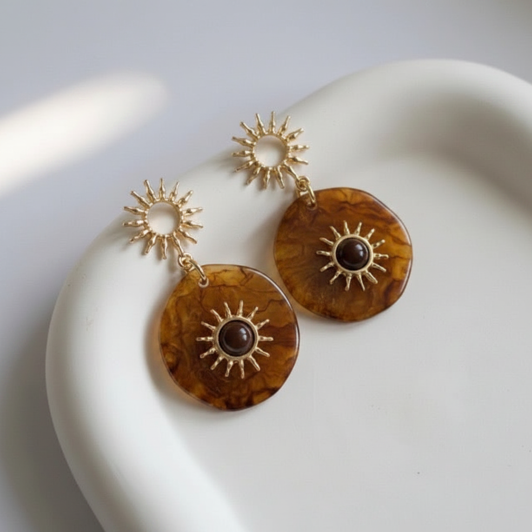 Pair of gold and brown earrings on a white surface