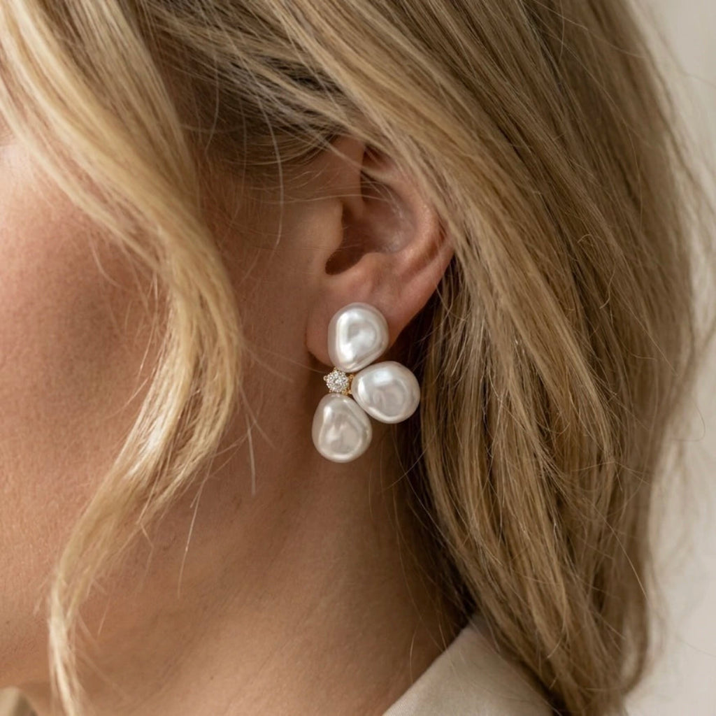 Pearl earrings worn by a person with blonde hair.
