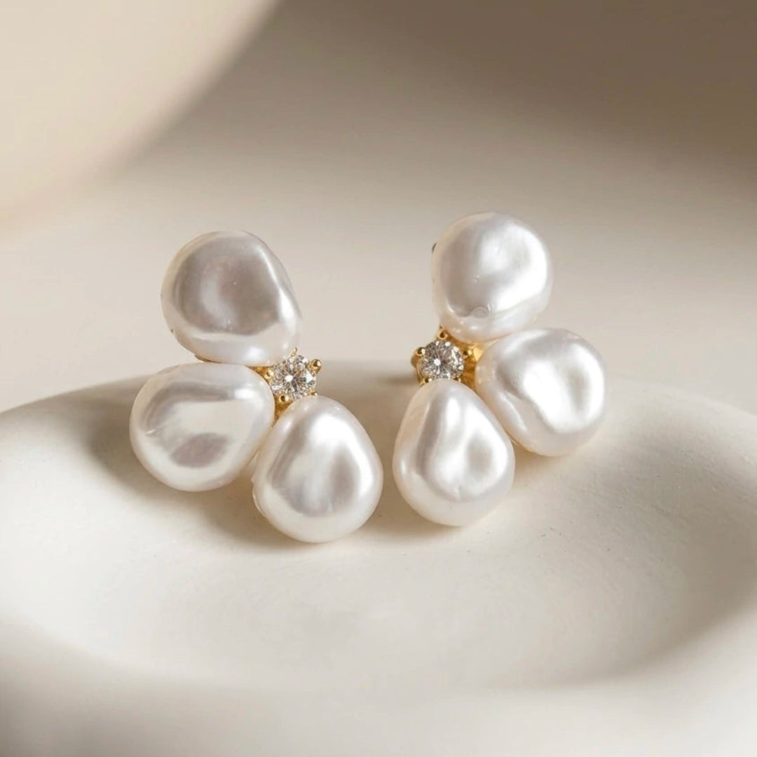 Pearl earrings with gold accents on a beige background